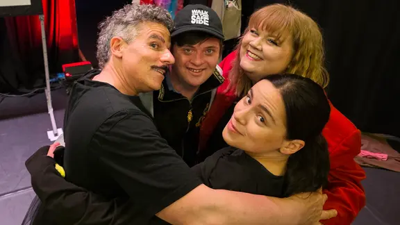Dario Redecker (Mitte) mit seiner Crew, die mit ihm bei "Ich zeige euch meine Welt" auf der Bühne steht. | NDR, Foto: Agnes Bührig Dario Redecker und drei weitere Schauspielerinnen und Schauspieler stehen im Kreis, umarmen sich und blicken in die Kamera.