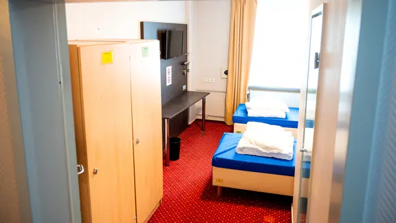 Zwei leere Betten stehen in einem Zimmer einer Notunterkunft. | dpa, Daniel Bockwoldt Zwei leere Betten stehen in einem Zimmer einer Notunterkunft.
