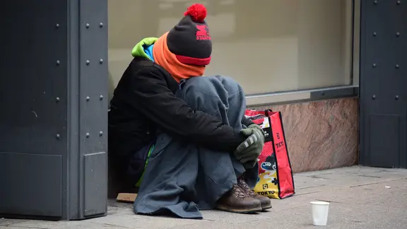 Ein warm angezogener Mann sitzt in der Innenstadt und sammelt Spenden. | dpa, Daniel Bockwoldt Ein warm angezogener Mann sitzt in der Innenstadt und sammelt Spenden.