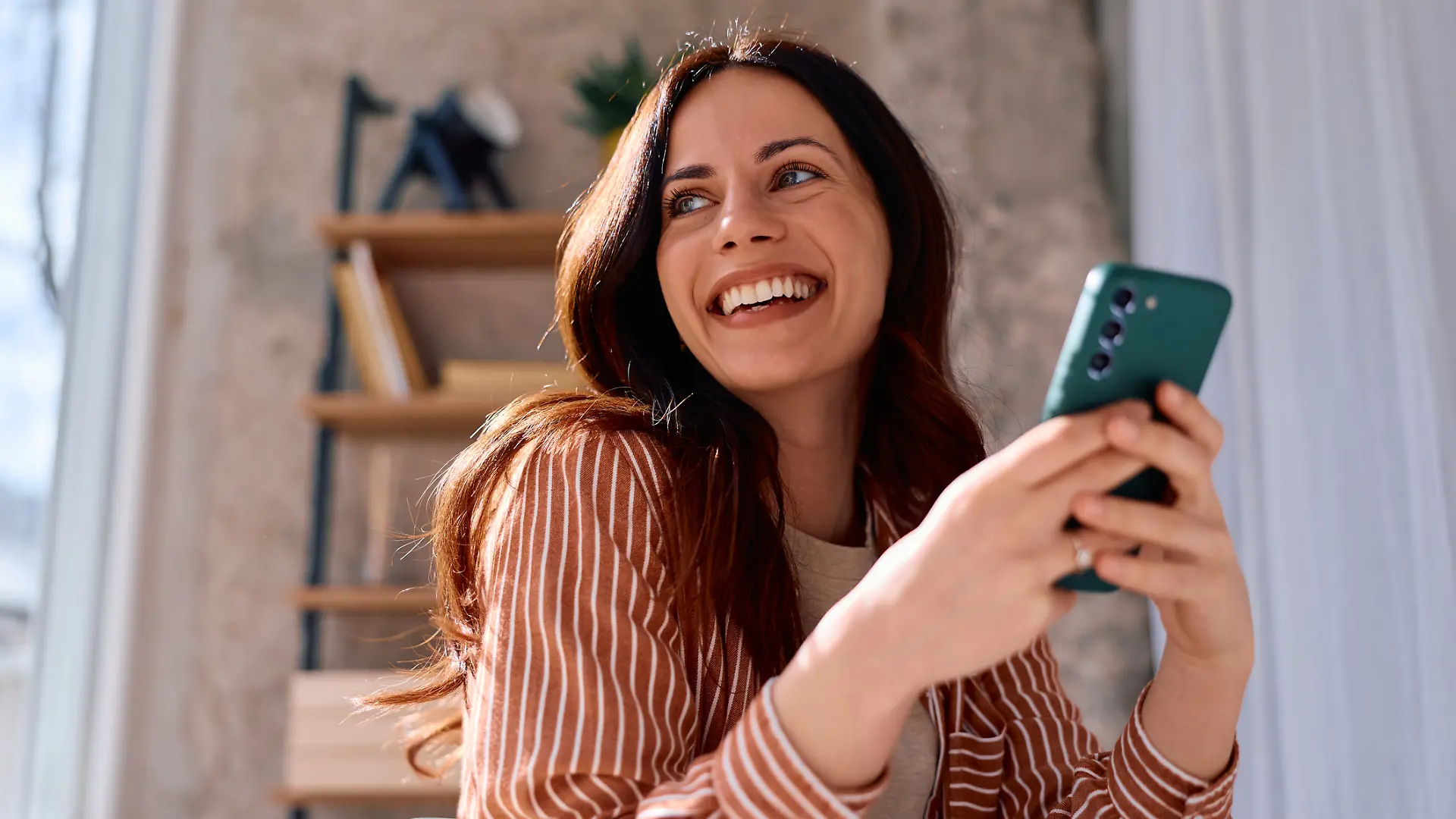Frau freut sich mit einem Smartphone in der Hand.