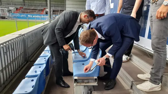 Kiels Oberbürgermeister Samet Yilmaz (Grüne) und der Chef der Staatskanzlei Dirk Schrödter (CDU) bauen symbolisch die ersten Sitze auf der Nordtribüne ab. | NDR, Marc-Kevin Kramhöft Sitzplätze im Holstein Kiel Stadion werden angebracht.