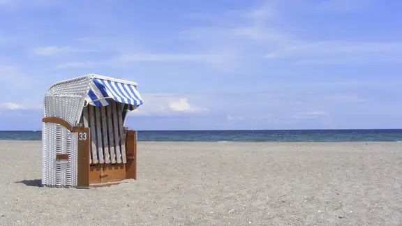 Ein Strandkorb steht bei schönem Wetter an der Ostsee.