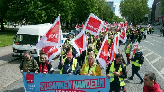 Verdi Gewerkschafts Mitglieder gehen mit rot weissen Fahnen und Plakaten Transparenten auf die Strasse