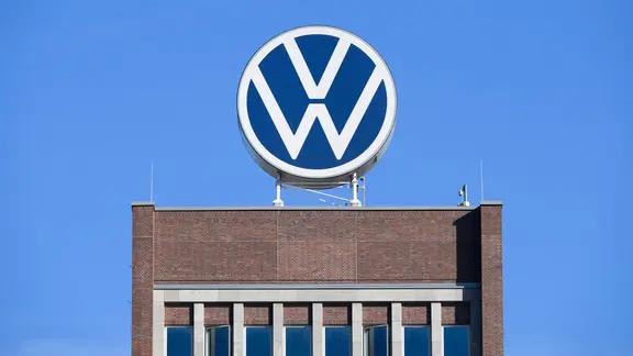 Das VW-Logo steht auf dem Markenhochhaus im Volkswagen Stammwerk. | Julian Stratenschulte/dpa Das VW-Logo steht auf dem Markenhochhaus im Volkswagen Stammwerk.
