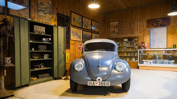 Ein alter grauer VW Käfer von Traugott Grundmann steht in einer Halle