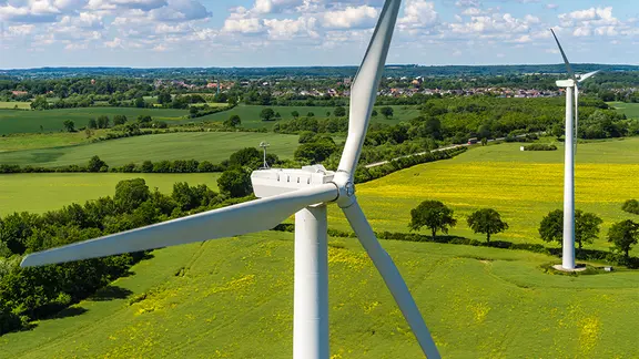 Eine Luftaufnahme zweier Windräder in einem Rapsfeld. | fotolia / Tim Siegert batcam, Tim Siegert Eine Luftaufnahme zweier Windräder in einem Rapsfeld.