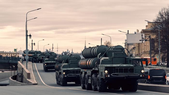 Mehrere schwere, mit je 5 großen Raketensilos beladene LKW fahren über eine Brücke.