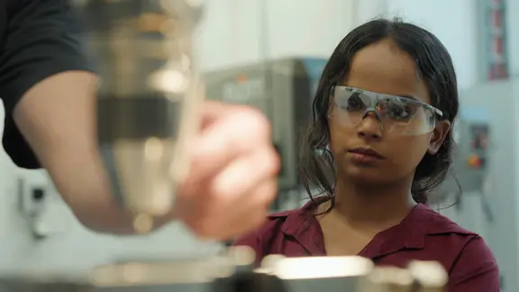 Kavita Auszubildende als Elektronikerin für Automatisierungstechnik aus Indien bei dem Pharmaunternehmen für Tiermedizin KVP in Kiel | NDR Eine Frau mit Schutzbrille blickt auf einem herstellungsprozess