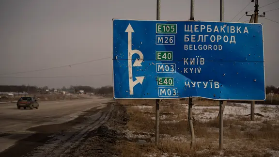 Archiv: Ein Auto fährt an einem von Kugeln und Granatsplittern beschädigten Straßenschild auf der Straße zur russischen Stadt Belgorod vorbei. | picture alliance/dpa/AP | Vadim Ghirda Archiv: Ein Auto fährt an einem von Kugeln und Granatsplittern beschädigten Straßenschild auf der Straße zur russischen Stadt Belgorod vorbei.