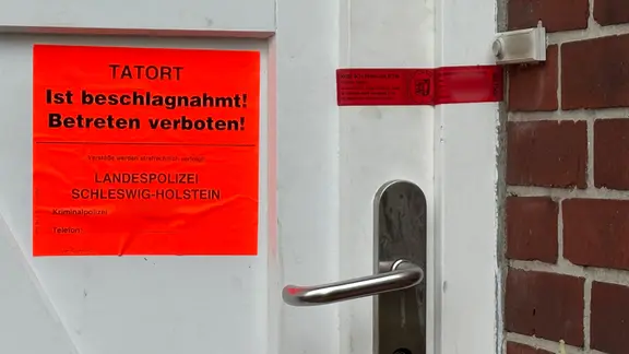 Ein roter Zettel mit dem Schriftzug Tatort ist beschlagnahmt! Betreten verboten! klebt an einer Tür. | NDR Ein roter Zettel mit dem Schriftzug Tatort ist beschlagnahmt! Betreten verboten! klebt an einer Tür.