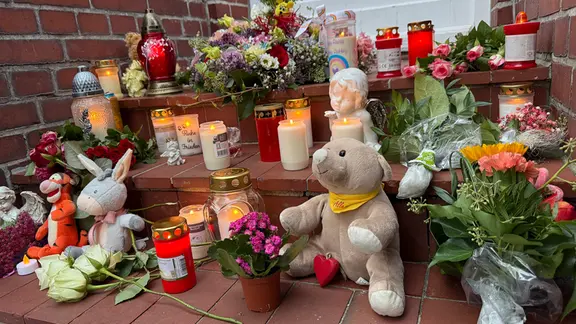 Kuscheltiere, Blumen und Kerzen liegen auf den Stufen eines Hauseingangs in Brunsbüttel. | NDR Kuscheltiere, Blumen und Kerzen liegen auf den Stufen eines Hauseingangs in Brunsbüttel.