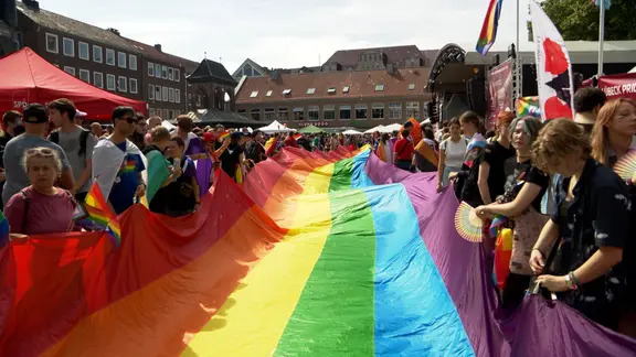 Beim Christopher-Street-Day in Lübeck wird eine große Regenbogenfahne entfaltet. | NDR, NDR Screenshots Beim Christopher-Street-Day in Lübeck wird eine große Regenbogenfahne entfaltet.