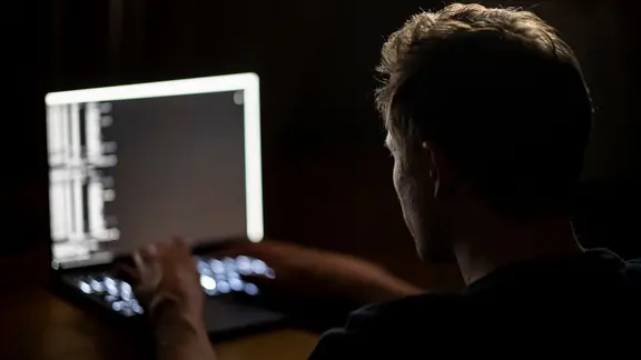 Ein Mann schreibt auf der Tastatur eines Laptops.