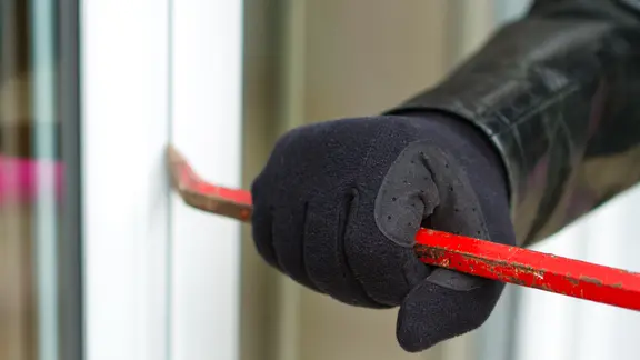 Der mutmaßliche Einbrecher ist polizeibekannt. (Themenbild) | Fotolia.com, sdecoret Einbrecher hebelt mit einem Brecheisen ein Fenster auf.
