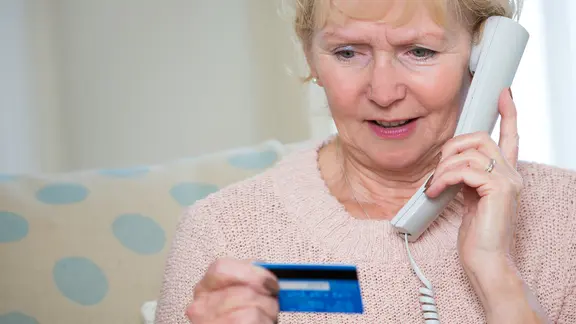 Seniorin telefoniert während sie ihren Blick auf eine EC-Karte in ihrer Hand richtet. | colourbox, - Seniorin telefoniert während sie ihren Blick auf eine EC-Karte in ihrer Hand richtet.