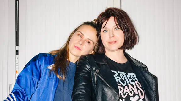Eva Reisinger (links) und Mareike Fallwickl lehnen ihre Köpfe aneinander und schauen in die Kamera.
