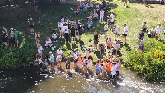 Einige Zuschauer sicherten sich beim Rapid Surfen besonders gute Plätze - Abkühlung inklusive. | NDR, Yannic Wittenberg Bei den Finals in Hannover kühlen sich Besucher in der Leine ab.