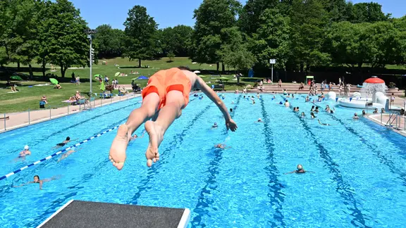 Ein Junge springt im Freibad Möhringen bei sommerlichen Temperaturen in ein Schwimmbecken. | picture alliance/dpa | Bernd Weißbrod Ein Junge springt im Freibad Möhringen bei sommerlichen Temperaturen in ein Schwimmbecken.