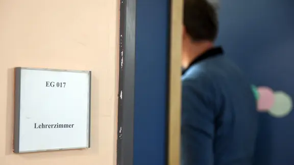 Eine Lehrkraft betritt ein Zimmer das mit "Lehrerzimmer" markiert ist. | picture alliance/dpa | Maurizio Gambarini, Maurizio Gambarini Eine Lehrkraft betritt ein Zimmer das mit "Lehrerzimmer" markiert ist.