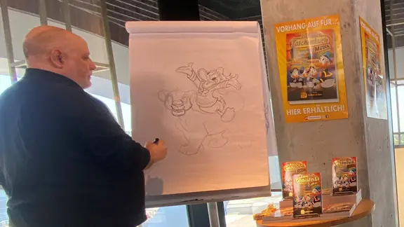 Fernando Güell zeichnet auf ein Flupchart einen Donald Duck | Mathias Heller Fernando Güell zeichnet auf ein Flupchart einen Donald Duck