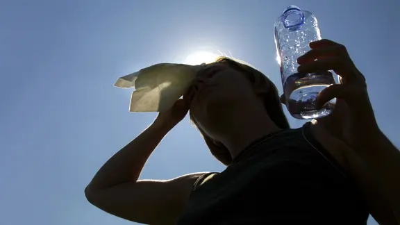 Eine Frau mit einer Flasche Wasser steht in der heißen Sonne. | colourbox Eine Frau mit einer Flasche Wasser steht in der heißen Sonne.