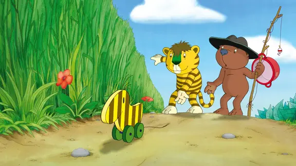 Tiger und Bär machen sich auf die Reise nach Panama. Eine Geschichte von Janosch. | IMAGO / United Archives Ein kleiner Tiger, ein Bär und eine Tigerente gehen an einem Feld vorbei.