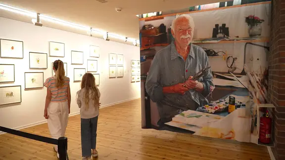 Zwei Kinder gehen in einer Ausstellung vorbei an einem großen Foto von Janosch | NDR Zwei Kinder gehen in einer Ausstellung vorbei an einem großen Foto von Janosch