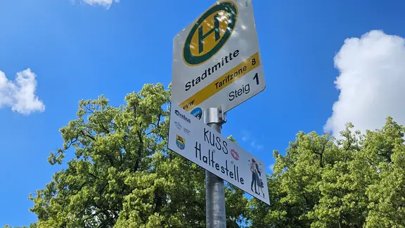 Das Schild "Kusshaltestelle" unter einem Bushaltestellenschild. | Jochen Arenz Das Schild "Kusshaltestelle" unter einem Bushaltestellenschild.