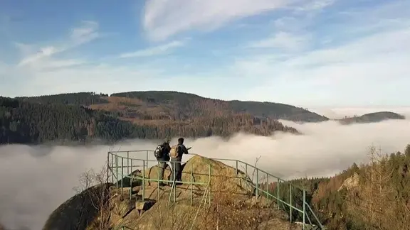Zwei Wanderer stehen auf dem Aussichtspunkt der Feigenbaumklippe über dem Okertal. | NDR Zwei Wanderer stehen auf dem Aussichtspunkt der Feigenbaumklippe über dem Okertal.