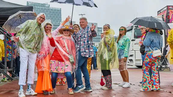 Teilnehmer des Schlagermoves 2026 stehen mit Regenschirmen und Regencapes auf dem Heiligengeistfeld. | Georg Wendt/dpa Teilnehmer des Schlagermoves 2026 stehen mit Regenschirmen und Regencapes auf dem Heiligengeistfeld.