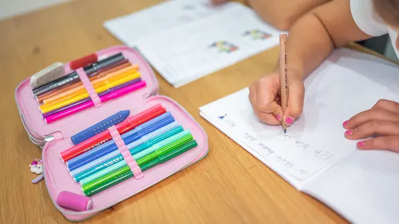 Ein Grundschüler und eine Grundschülerin sitzen in einem Klassenzimmer bei einem Unterricht.