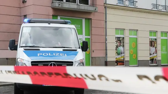 Ein Einsatzwagen der Polizei steht hinter einem rot-weißen Absperrband. | MITTELDEUTSCHER RUNDFUNK Ein Einsatzwagen der Polizei steht hinter einem rot-weißen Absperrband.