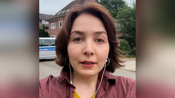 NDR Reporterin Lisa Göllert spricht mit Kopfhörern in ihr Smartphone. | NDR NDR Reporterin Lisa Göllert spricht mit Kopfhörern in ihr Smartphone.