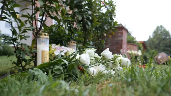 Blumen und Kerzen liegen und stehen vor dem Gebäude einer Jugendeinrichtung. | Jörn Hünecke/dpa Blumen und Kerzen liegen und stehen vor dem Gebäude einer Jugendeinrichtung.