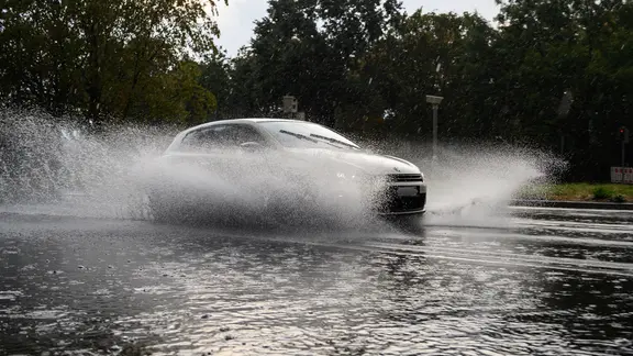 Ein Auto fährt bei starkem Regen durch eine überschwemmte Straße in Hannover. | picture alliance/dpa | Christophe Gateau Ein Auto fährt bei starkem Regen durch eine überschwemmte Straße in Hannover.