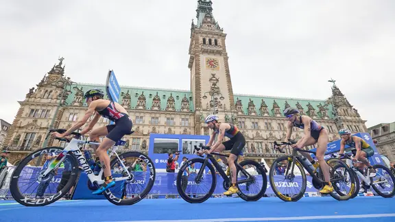 Teilnehmerinnen des Triathlons fahren mit dem am Hamburger Rathaus vorbei. | picture alliance/dpa | Georg Wendt, Georg Wendt Teilnehmerinnen des Triathlons fahren mit dem am Hamburger Rathaus vorbei.