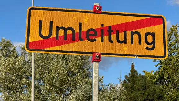 Ein Schild hat das Wort "Umleitung" durchgestrichen.
