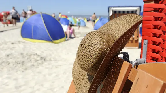 Bei hochsommerlichen Temperaturen hängt am 21. Juli 2013 der Strohhut einer Nordseeurlauberin an einem Strandkorb in Bensersiel. | picture alliance/dpa, Ingo Wagner Bei hochsommerlichen Temperaturen hängt am 21. Juli 2013 der Strohhut einer Nordseeurlauberin an einem Strandkorb in Bensersiel.