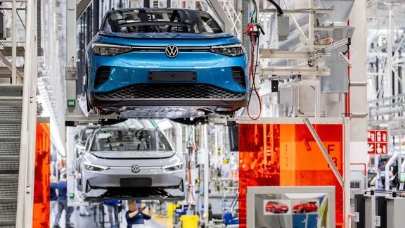Mitarbeitende arbeiten im Werk von Volkswagen an einem Fließband an Fahrzeugen. | Hauke-Christian Dittrich/dpa Mitarbeitende arbeiten im Werk von Volkswagen an einem Fließband an Fahrzeugen.