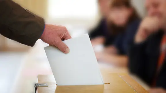 Hand wirft Umschlag in Wahlurne | Fotolia.com, Christian Schwier Hand wirft Umschlag in Wahlurne