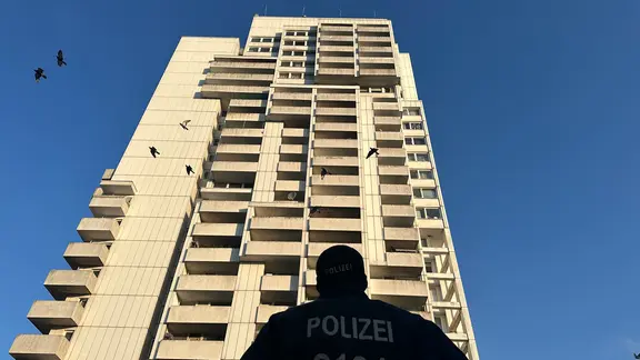 Polizeiwagen stehen im Kieler Stadtteil Mettenhof vor einem weißen Hochhaus. | Samir Chawki / NDR Polizeiwagen stehen im Kieler Stadtteil Mettenhof vor einem weißen Hochhaus.