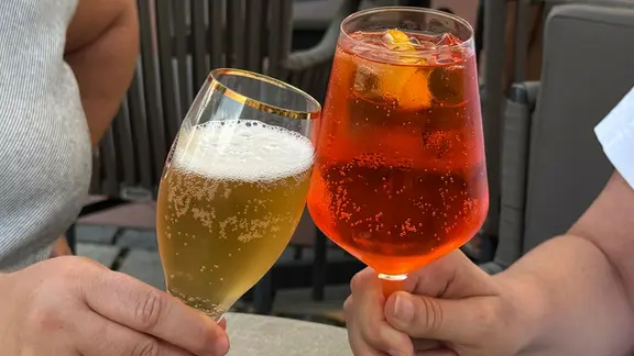 Zwei Menschen stoßen an mit Bier und Aperol Spritz. | picture alliance / M.i.S. | Bernd Feil Zwei Menschen stoßen an mit Bier und Aperol Spritz.