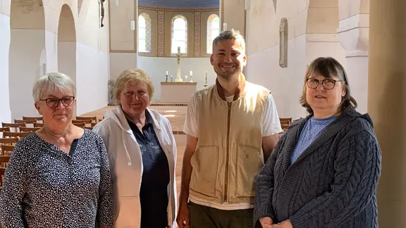 Ein Mann und drei Frauen stehen lächelnd in einer Kirche