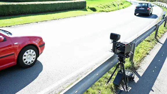 Eine mobile Messeinheit steht am Straßenrand und überwacht den fließenden Verkehr. | IMAGO Images/diebildwerft Eine mobile Messeinheit steht am Straßenrand und überwacht den fließenden Verkehr.