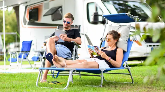 Ein Paar sitzt vor einem Wohnmobil | picture alliance / dpa Themendienst Ein Paar sitzt vor einem Wohnmobil