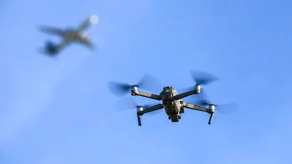 Eine Drohne fliegt vor einem startenden Flugzeug in der Luft. | Jan Woitas Eine Drohne fliegt vor einem startenden Flugzeug in der Luft.