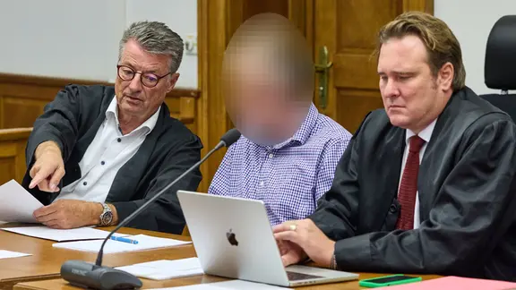 Ein Angeklagter sitzt vor Beginn des Prozesses im Gerichtssaal des Landgerichts Lüneburg zwischen seinen Anwälten Rüdiger Proest (l) und Christoph Grabitz. | dpa-Bildfunk, Georg Wendt Ein Angeklagter sitzt vor Beginn des Prozesses im Gerichtssaal des Landgerichts Lüneburg zwischen seinen Anwälten Rüdiger Proest (l) und Christoph Grabitz.
