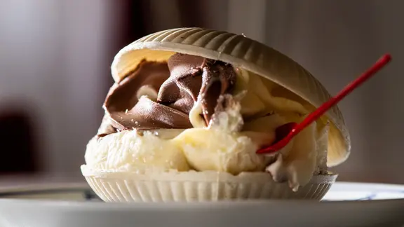 Schoko-Vanille-Softeis in einer Muschelwaffel mit Namensloeffelchen, eine typische Nachspeise aus der ehemaligen DDR, ist am 09.10.2018 im Restaurant Volkskammer in Berlin zu sehen. | picture alliance / dpa Themendienst | Franziska Gabbert Schoko-Vanille-Softeis in einer Muschelwaffel mit Namensloeffelchen, eine typische Nachspeise aus der ehemaligen DDR, ist am 09.10.2018 im Restaurant Volkskammer in Berlin zu sehen.