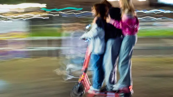 Drei Jugendliche fahren gemeinsam auf einem E-Scooter. | picture alliance/dpa | Wolfram Steinberg Drei Jugendliche fahren gemeinsam auf einem E-Scooter.