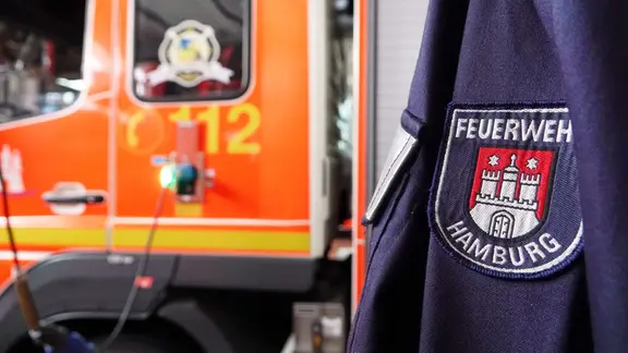 Die Hamburger Feuerwehr brachte in Bramfeld mehrere Menschen in Sicherheit. (Symbolfoto) | Julian Weber/dpa Eine Jacke mit der Aufschrift "Feuerwehr Hamburg" hängt in der Feuer- und Rettungswache Berliner Tor in Berlin
